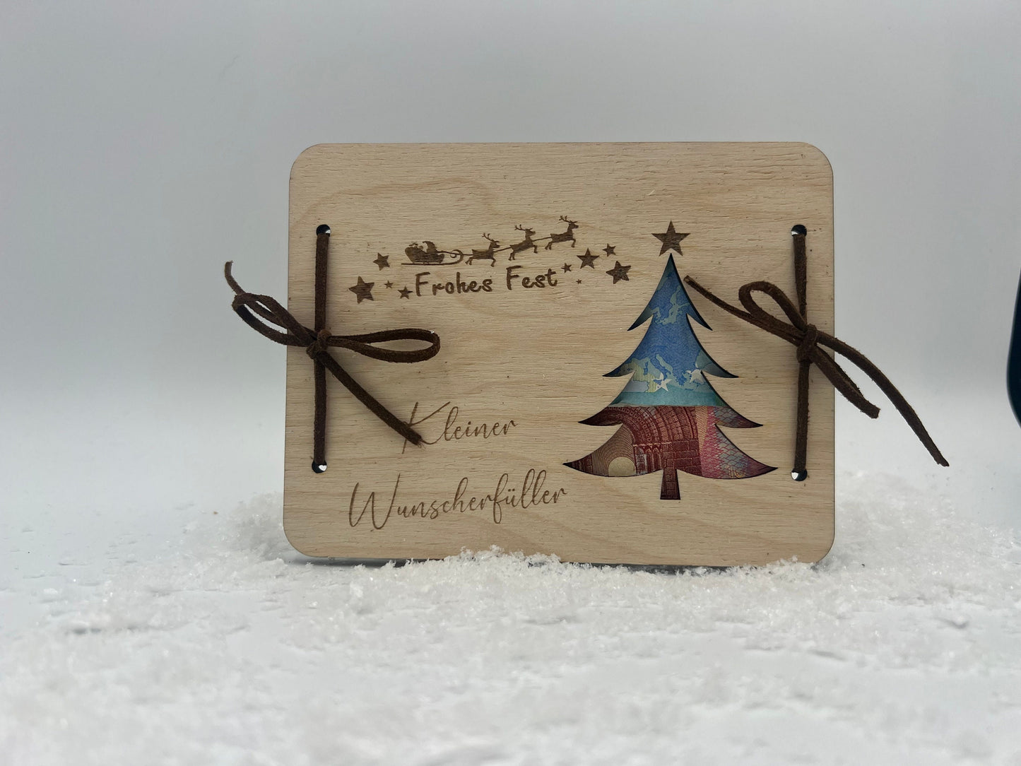 Holz-Geschenkkarte mit Weihnachtsbaum-Motiv, Frohes Fest-Gravur und Platz für Geldgeschenke, verziert mit Bändern.